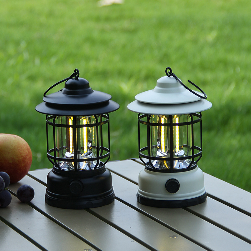Gray multi-function camping lantern hanging from a tree branch