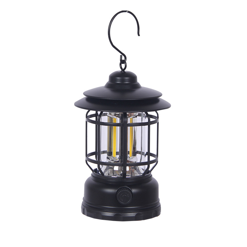 Black and white retro camping lanterns lit on a folding table at a campsite