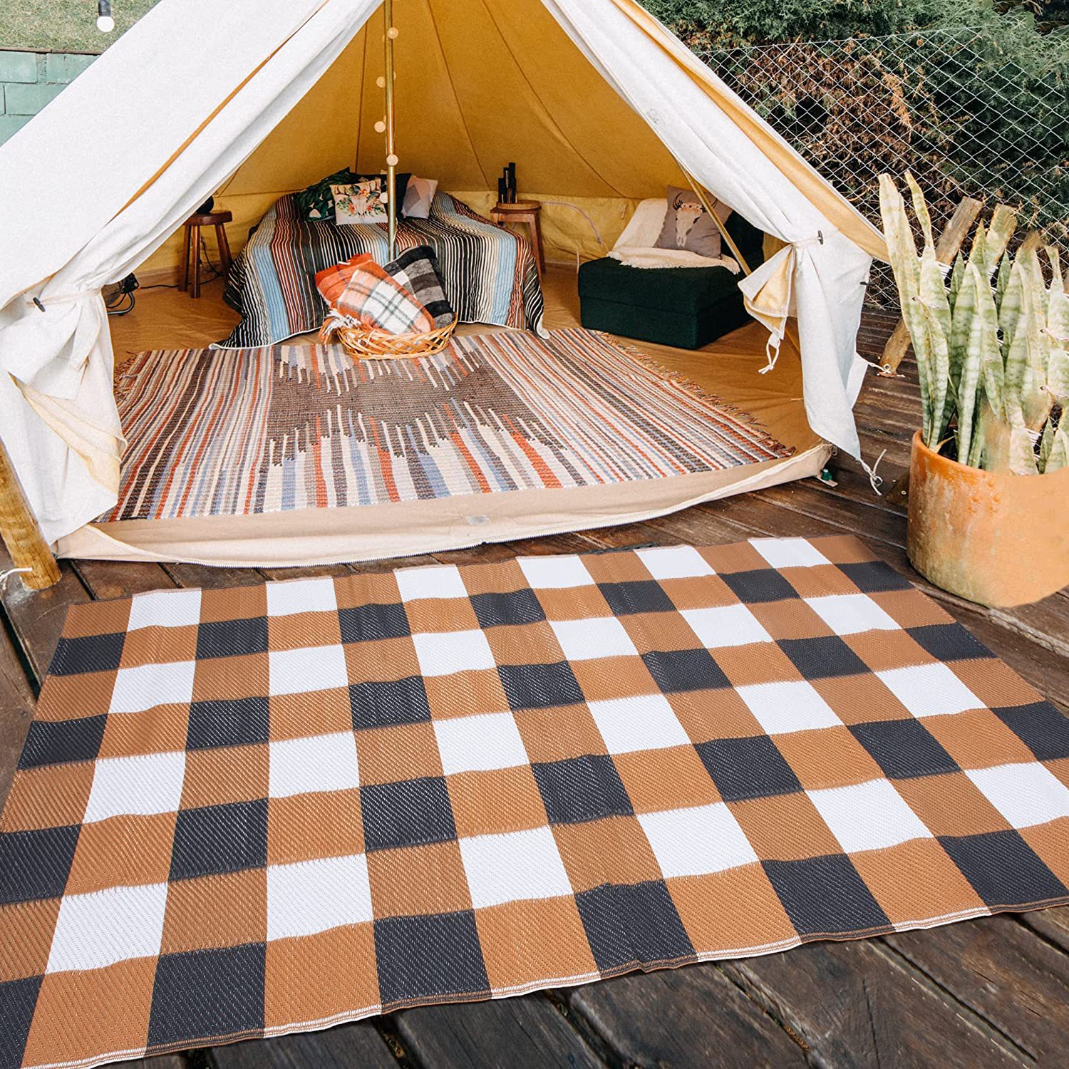 Outdoor camping ground mat laid on a wooden platform beside a tent at a campsite